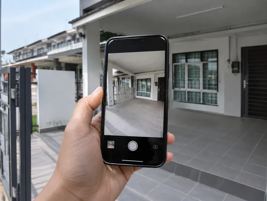 Hand holding a phone photographing an empty car porch to send to Eave on WhatsApp